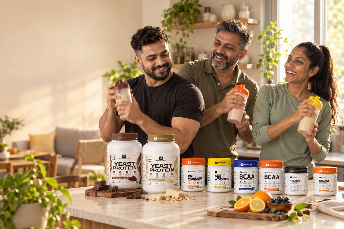Friends laughing in a kitchen while shaking EVRYDAY protein shakes